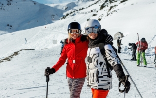 Two skiers on the mountain of Snowbird and Alta ski resorts hugging